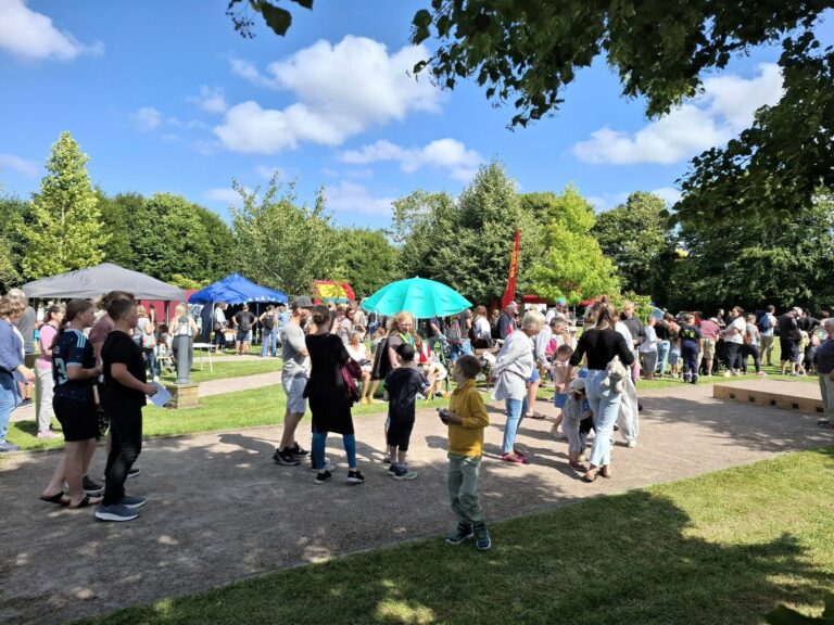 Besucherinnen und Besucher auf dem Spielefest 2026 in Hooksiel mit Marktständen, Pavillons und zahlreichen Familien unter blauem Himmel.