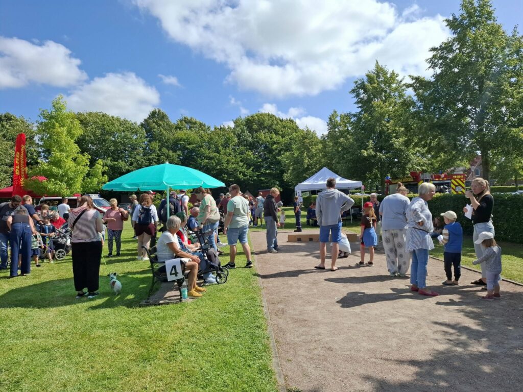 Familien und Besucherinnen und Besucher nehmen an verschiedenen Mitmachaktionen beim Spielefest 2026 in Hooksiel teil und genießen das vielfältige Programm auf dem sonnigen Festgelände im Park.