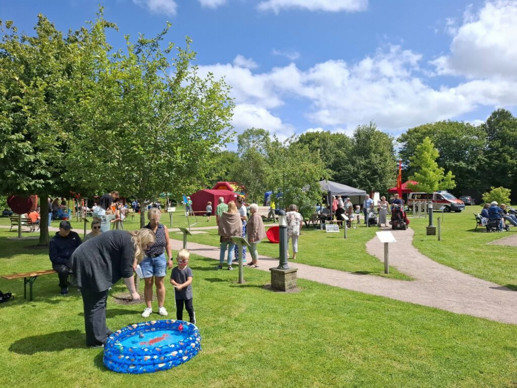 Familien und Kinder besuchen das Spielefest 2026 in Hooksiel und erkunden verschiedene Mitmachstationen sowie Aktionsstände auf dem weitläufigen Parkgelände bei sonnigem Wetter.